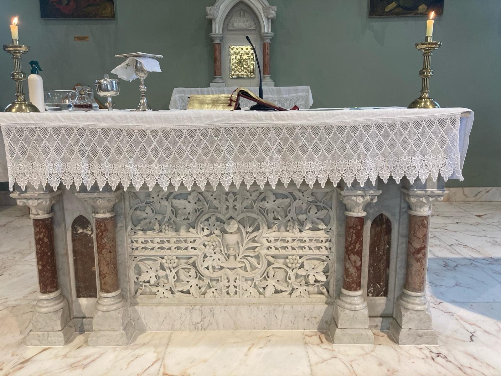 Altar de igreja católica com toalha de renda e castiçais acesos